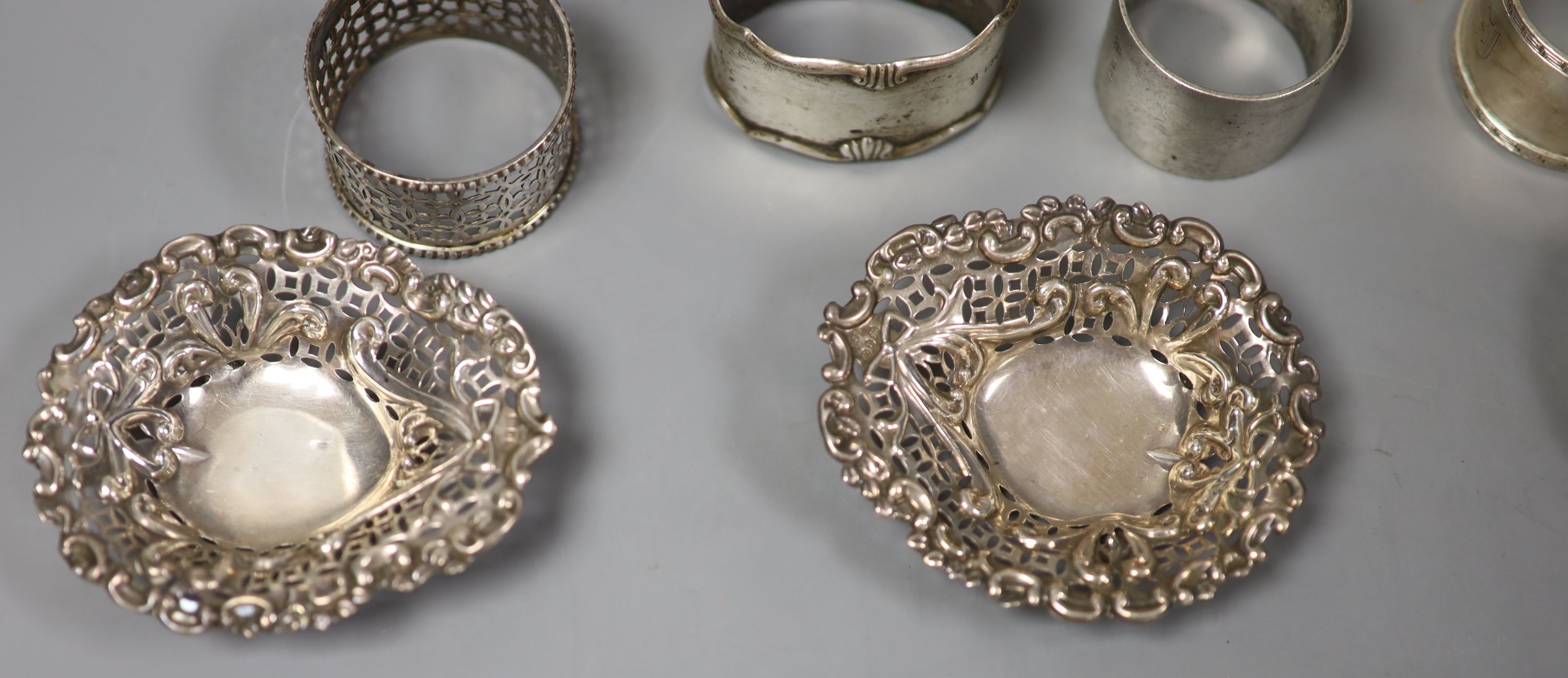 A pair of Edwardian silver napkin rings, London, 1906, three others and four pierced silver bonbon dishes